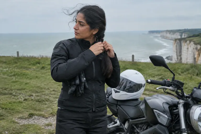 Sur un parking des falaises du pays de Caux, une motarde tresse ses longs cheveux sur la nuque avant de mettre son casque intégral blanc
