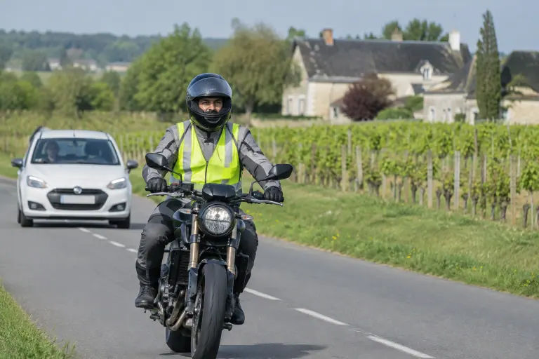 Sur une petite route entre les vignes près de Saumur, un candidat au permis moto en dossard roule, suivi à distance par la voiture de l’inspecteur
