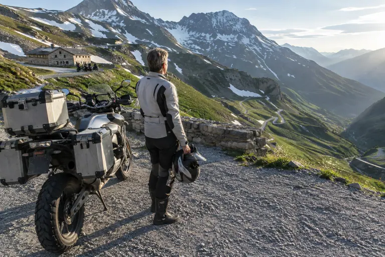 Au sommet d’un col savoyard, une motarde d’une quarantaine d’années, casque à la main, regarde les lacets qu’elle vient de gravir près de son gros trail
