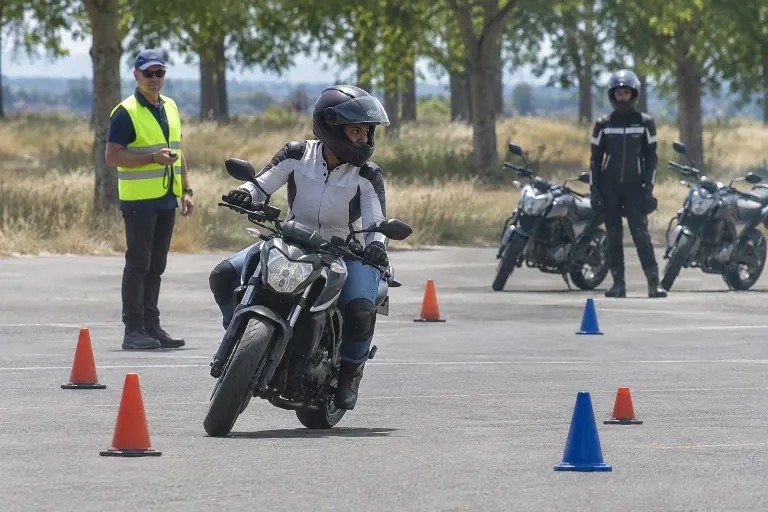 Sur une piste de moto-école près de Toulouse, une élève équipée négocie un demi-tour lent entre les cônes sous l’œil de son moniteur, chronomètre en main