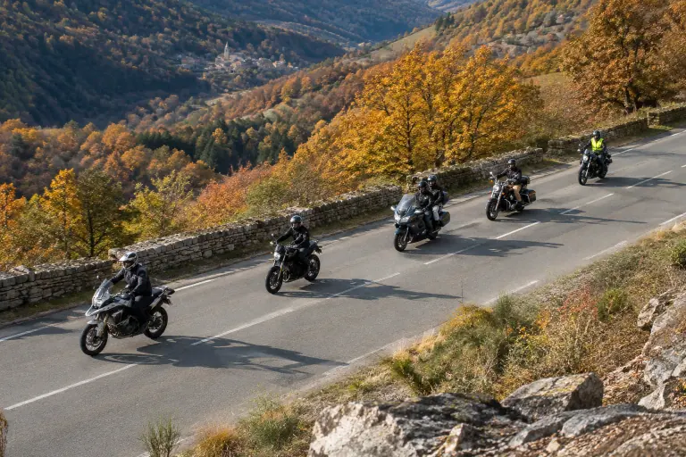 Cinq motos roulent en quinconce sur une large départementale des Cévennes bordée de châtaigniers, le serre-file reconnaissable à son gilet jaune fluo